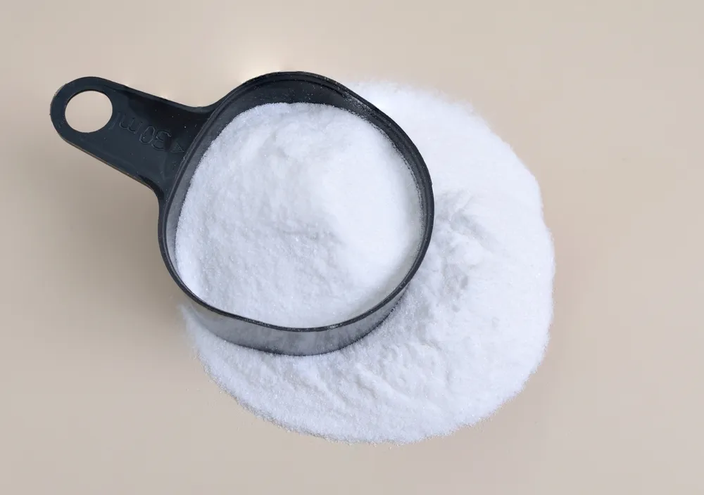 Pequeña pala negra de plástico con una pila de bicarbonato de sodio